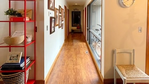 A hallway with a wooden floor, a red shelving unit with various items, a white chair, and a wall clock. - Meadow House 7 / 2 BR / 2 BA Sleeps 6+ (Sunriver)