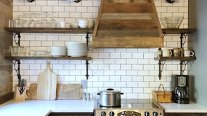A kitchen with white tiled backsplash, wooden shelves, and a stainless steel stove. - Meadow House 7 / 2 BR / 2 BA Sleeps 6+ (Sunriver)