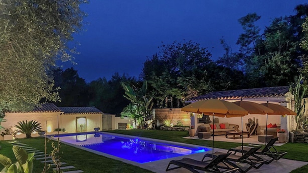 A backyard with a swimming pool, outdoor furniture, and a patio area.