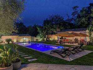 A backyard with a swimming pool, outdoor furniture, and a patio area.
