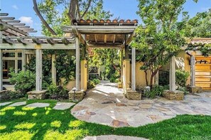 Stroll through the tranquil outdoor space, surrounded by lush greenery and a beautifully designed pergola.