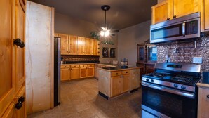 A kitchen with wooden cabinets, a central island, a built-in oven, and a microwave. - The Hidden Gem in downtown Connersville (Connersville)