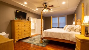 A bedroom with a wooden bed, a ceiling fan, a dresser, and a television on the wall. - The Hidden Gem in downtown Connersville (Connersville)