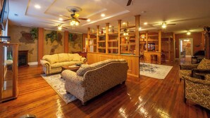 A spacious living room with wooden flooring, a fireplace, and a large bookshelf. - The Hidden Gem in downtown Connersville (Connersville)