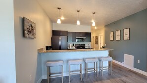 Une cuisine moderne avec un coin bar, des appareils en acier inoxydable et un mur de couleur bleu clair.