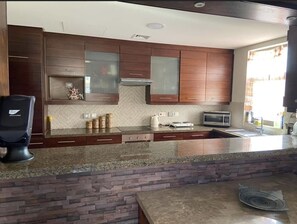 A modern kitchen with granite countertops, wooden cabinets, and a built-in stove. - Lovely 2 bedrooms serviced apartment with apool (Dead sea swemeh)