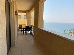 A balcony with a view of the sea, a table with chairs, and a railing. - Lovely 2 bedrooms serviced apartment with apool (Dead sea swemeh)