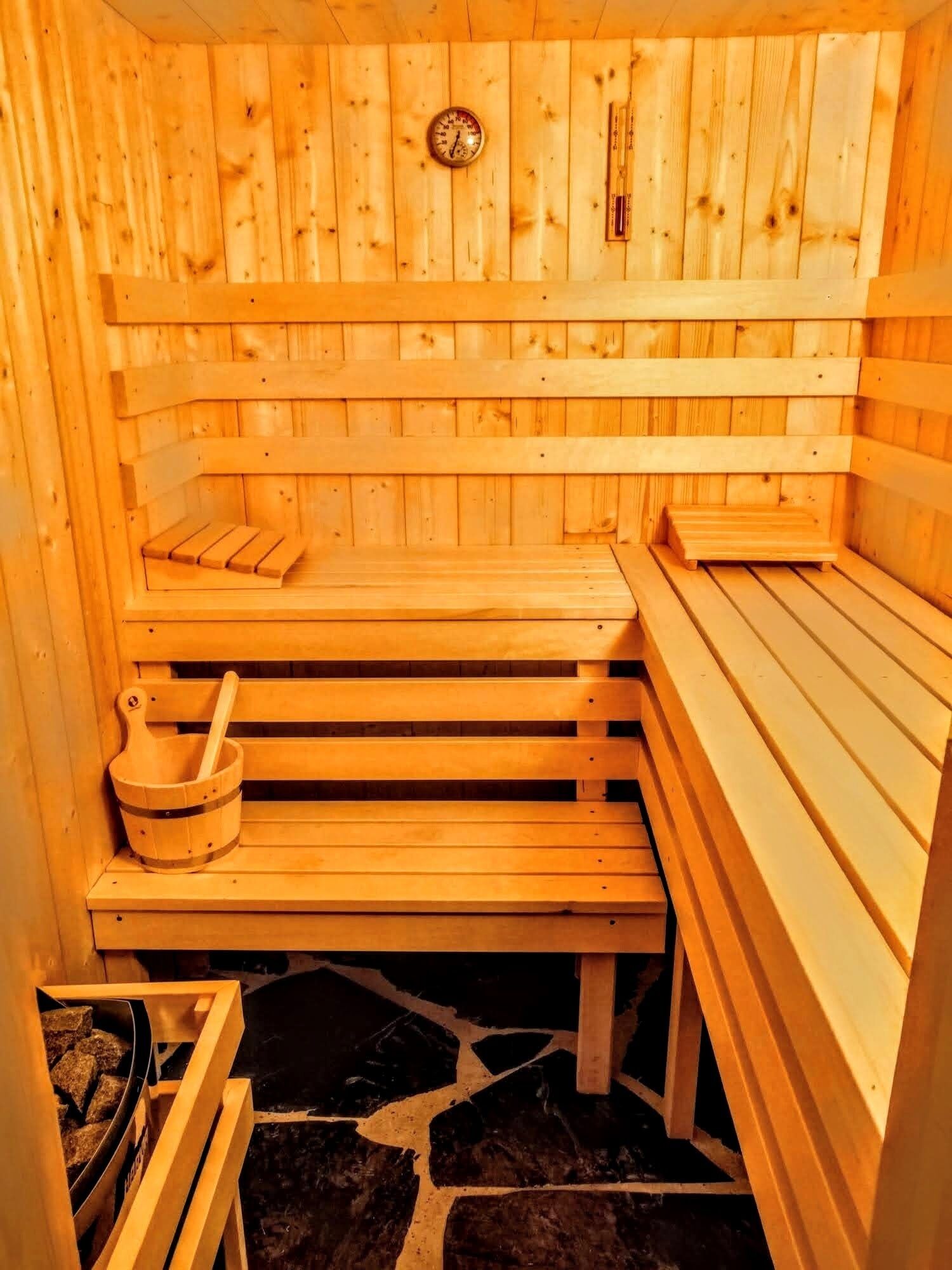 Un sauna avec des bancs en bois et un sol en pierre.