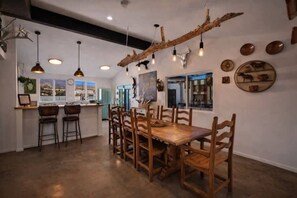 Un espace repas comprenant une table et des chaises en bois, des luminaires suspendus et des éléments de décoration fixés au mur.