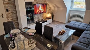 A modern living room with a fireplace, a dining area, and a cozy seating arrangement. - Exclusive and bright apartment in the centre (Kassel)