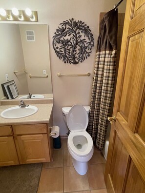 A bathroom with a toilet, sink, and a decorative wall piece.
