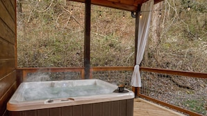 A hot tub on a wooden deck with a view of a wooded area.