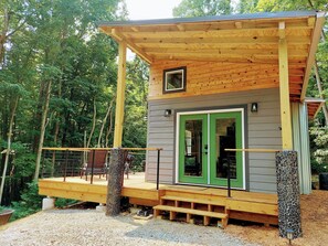 A wooden cabin with a green door, a small window, and a balcony.