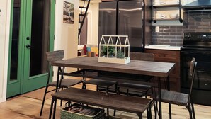 Una cocina moderna con vigas de madera, una puerta verde, una mesa de comedor con bancos y una lámpara colgante.