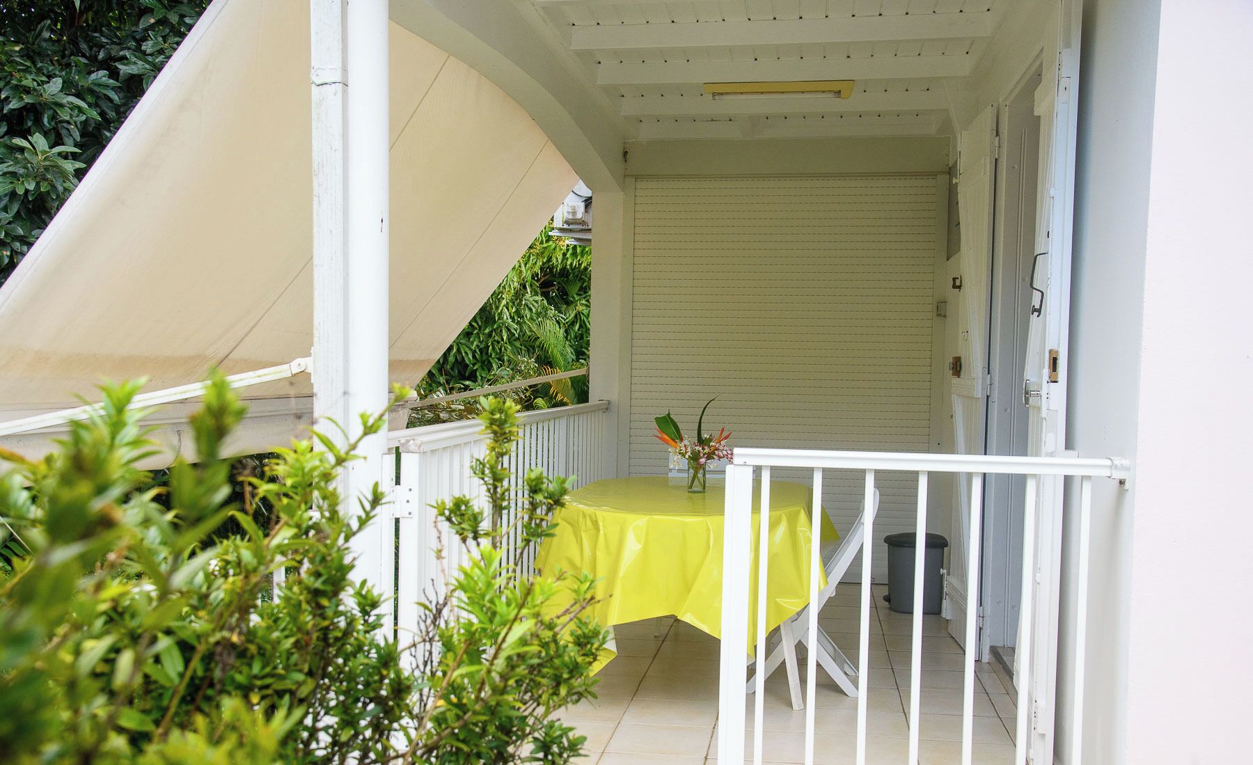 A covered outdoor area with a yellow table and white railing.