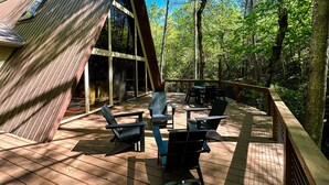 Een houten terras met een tafel en stoelen, omgeven door bomen.