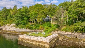 A stone structure with a grassy area and white chairs, surrounded by dense greenery and trees. - Luxurious island home on the water, 30 minute ferry ride from Portland Maine (Portland)