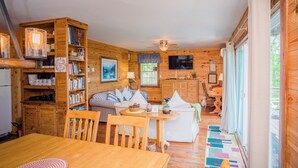 A cozy cabin interior with a dining area, a sofa, a television, and a wooden bookshelf. - Cozy mountain retreat with spectacular view to unwind and relax. Pet friendly ! (Glade Valley)