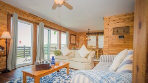 A cozy cabin interior with a wooden ceiling, a sofa, a striped couch, a coffee table, and a chessboard. - Cozy mountain retreat with spectacular view to unwind and relax. Pet friendly ! (Glade Valley)