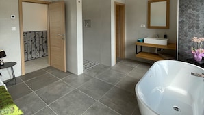 A modern bathroom with a freestanding bathtub, a vanity with a mirror, and a shower area.