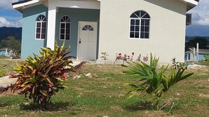 A single-story house with a white exterior and a blue accent wall, featuring a front door, two windows, and a small porch. - Loodik Vacation Home Brompton Manor  (Speculation)
