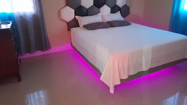 A bedroom with a bed, a headboard, and a nightstand. - Loodik Vacation Home Brompton Manor  (Speculation)