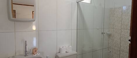 Un bagno con lavandino, WC e cabina doccia in vetro.