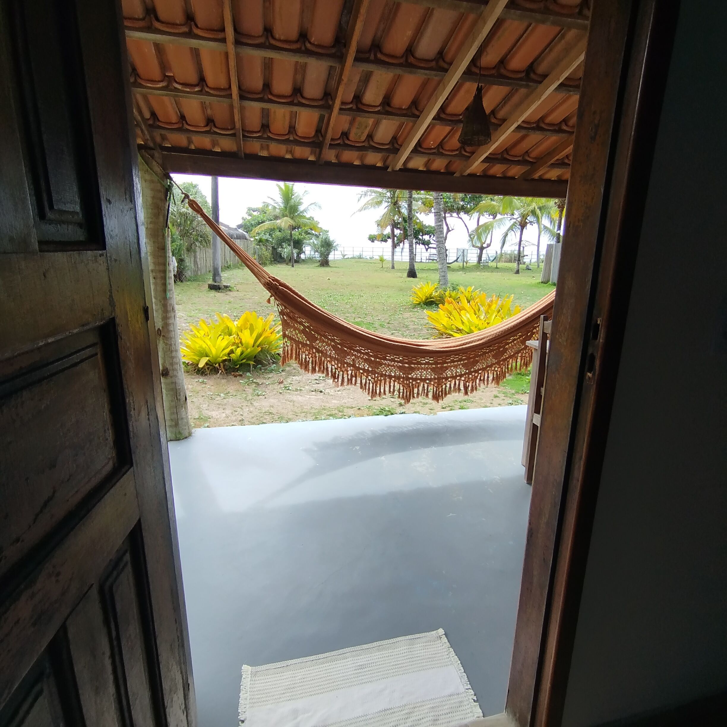 Un acceso que da a una hamaca y un espacio cubierto de césped y plantas amarillas.
