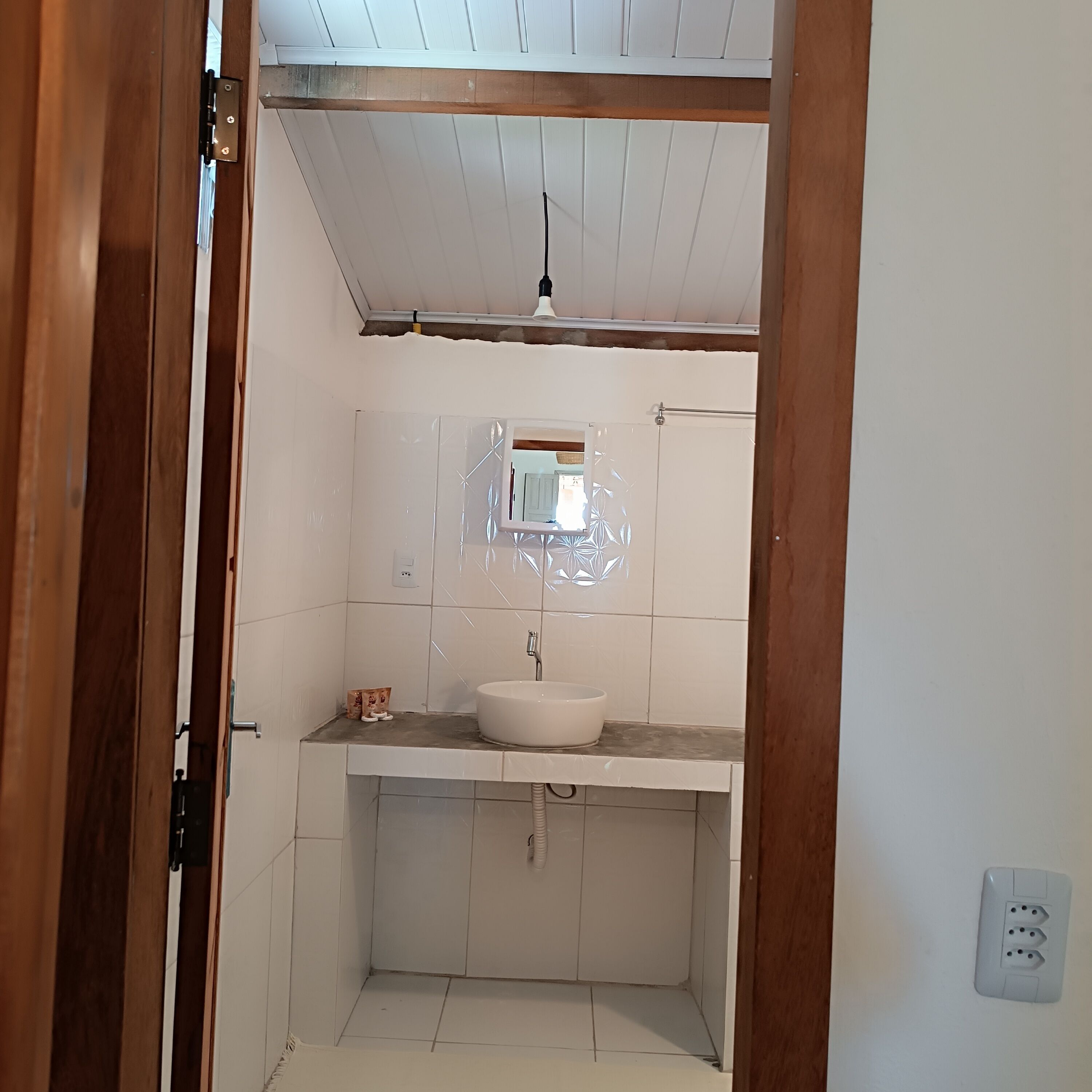 Une petite salle de bain avec un lavabo blanc, un miroir et une douche.