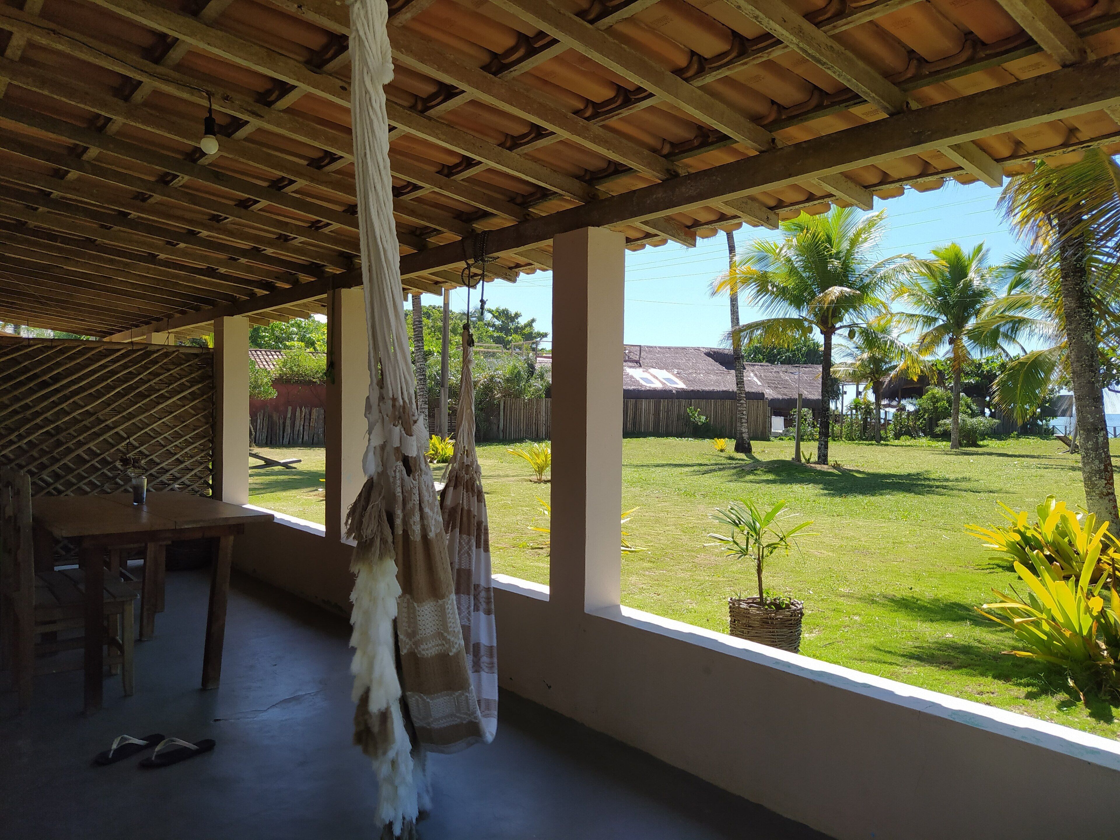 Ein überdachter Patio-Bereich mit Blick auf einen Rasen und Palmen.