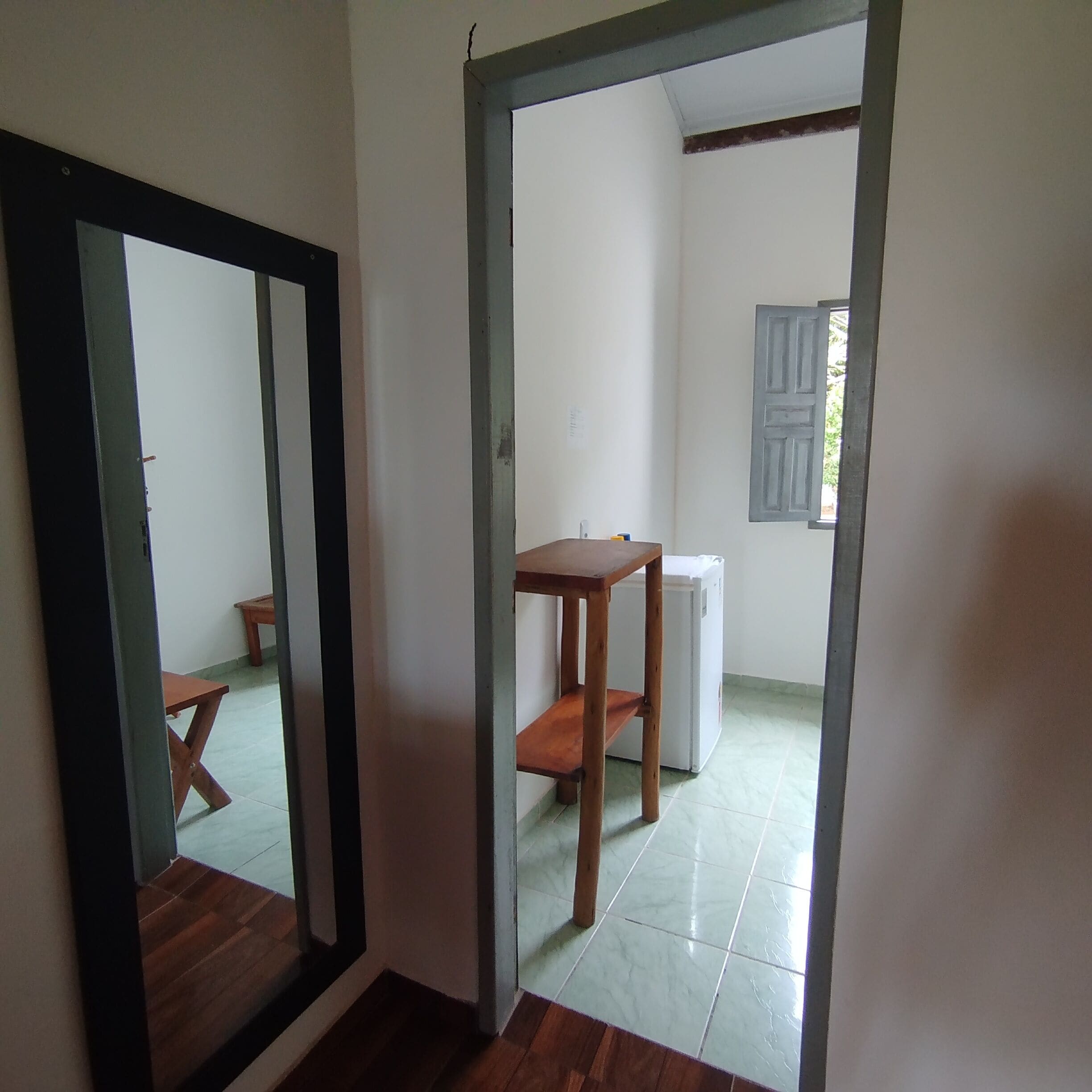 A room with a wooden floor, a white door, a small table, and a white appliance.
