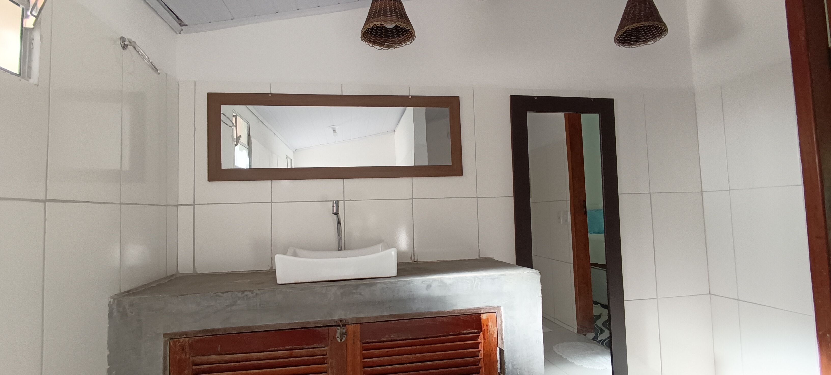 A bathroom with a white sink, a large mirror, and a wooden cabinet.