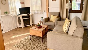 Ein gemütliches Wohnzimmer mit Fernseher, zwei Sofas, einem Couchtisch und einem gemusterten Teppich.