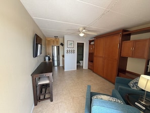 Un espacio habitable compacto con kitchenette, comedor, baño y zona de estar con sofá y mesa.