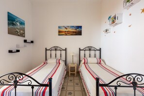 Una stanza con due letti, un tavolino e decorazioni alle pareti, tra cui quadri e mensole con piante.