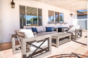 An outdoor patio with a wooden sofa, two armchairs, and a small table.