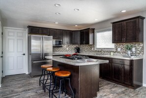 Enjoy cooking in this well-equipped kitchen with dark cabinetry, stainless steel appliances, and a spacious island with bar stools.
