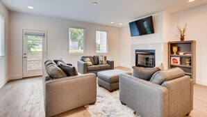 A spacious living room with a fireplace, two sofas, and a flat-screen TV mounted on the wall. - The Lischey House-East Nashville (Nashville)