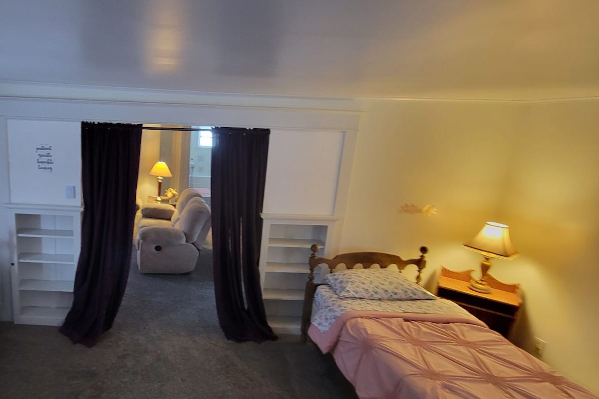 A bedroom with two single beds, a desk, and a chair.