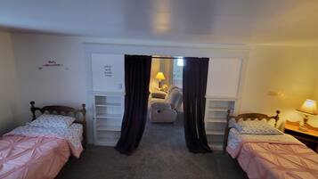 A bedroom with two single beds, a desk, and a chair.
