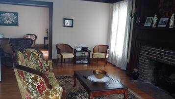 A living room with a fireplace, two armchairs, a coffee table, and a bookshelf.