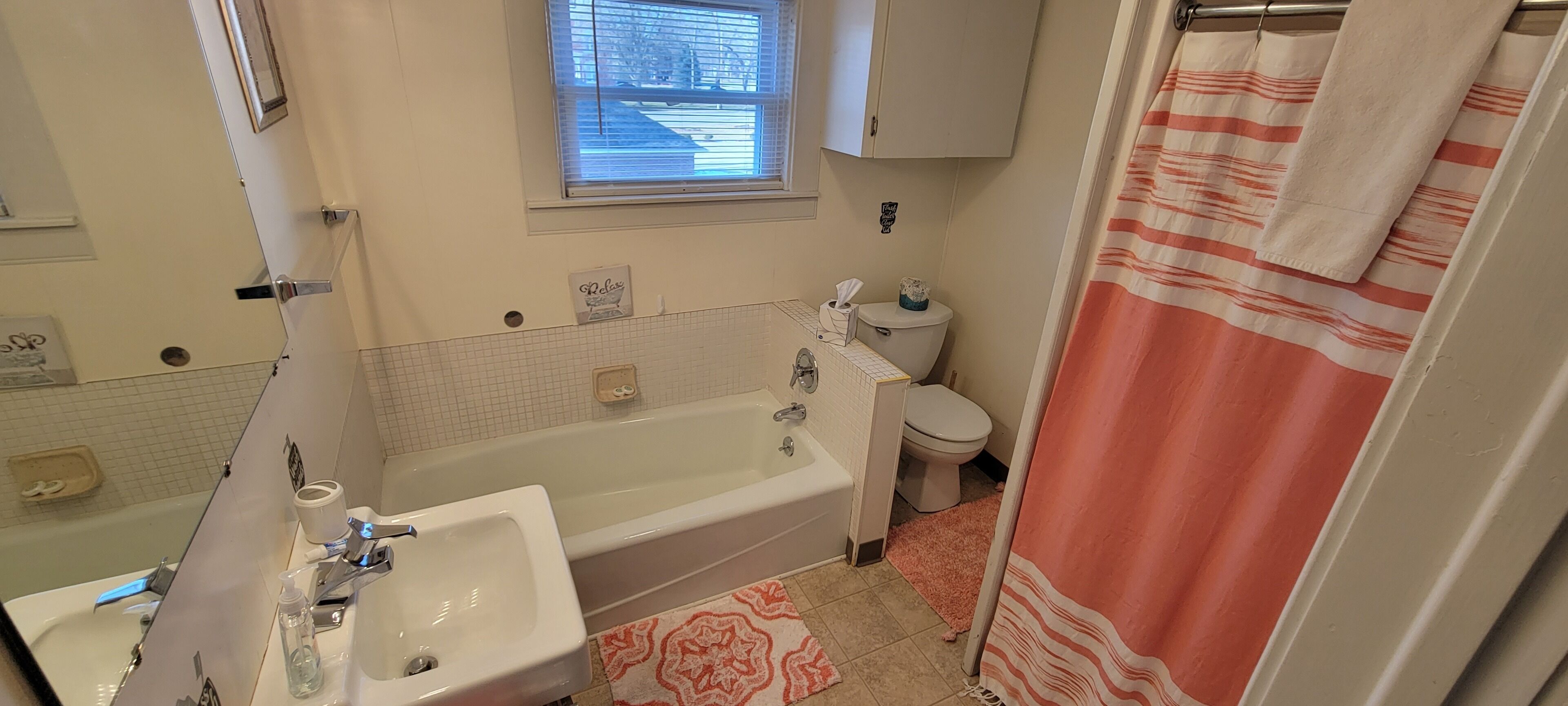 Un baño con bañera, lavamanos, inodoro y ventana.