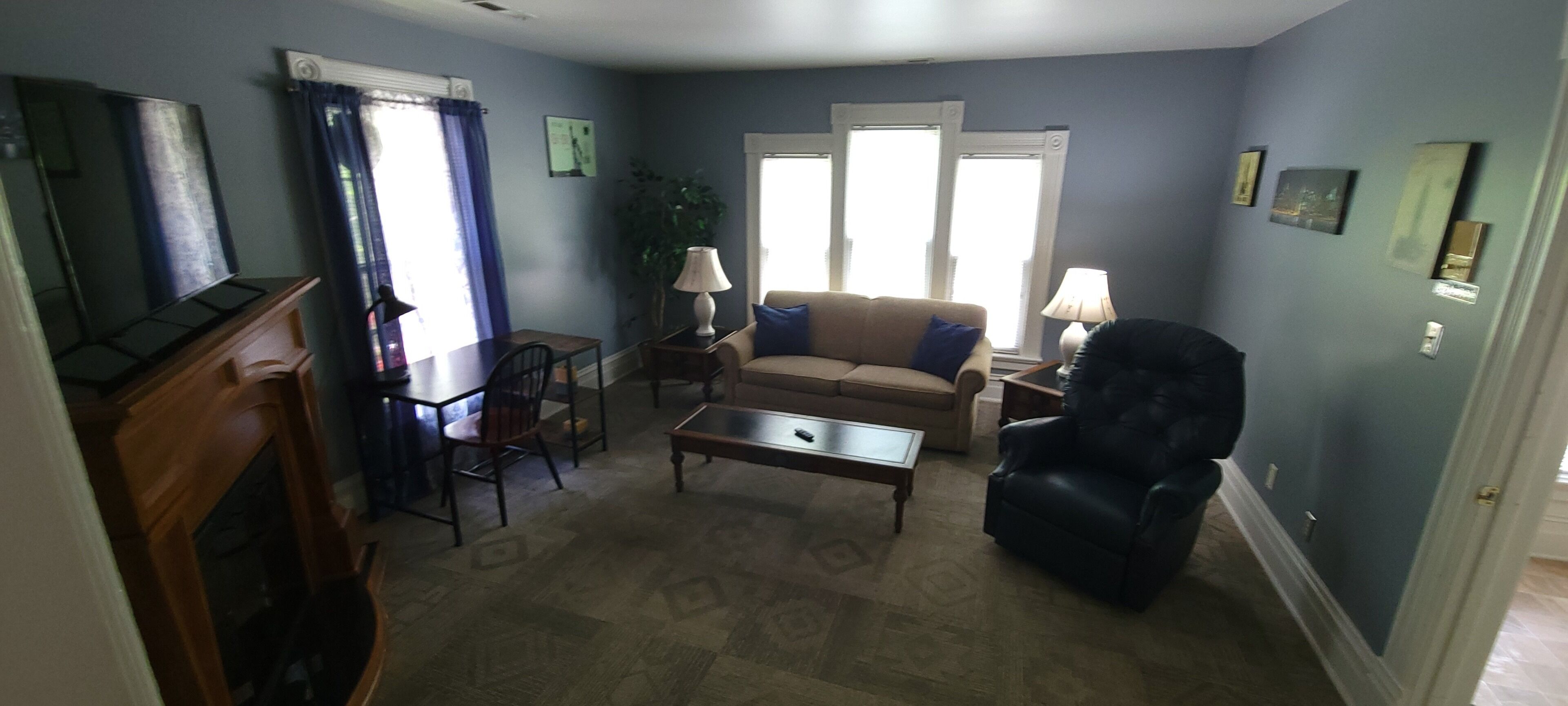 A living room with a sofa, armchair, coffee table, and a TV stand.