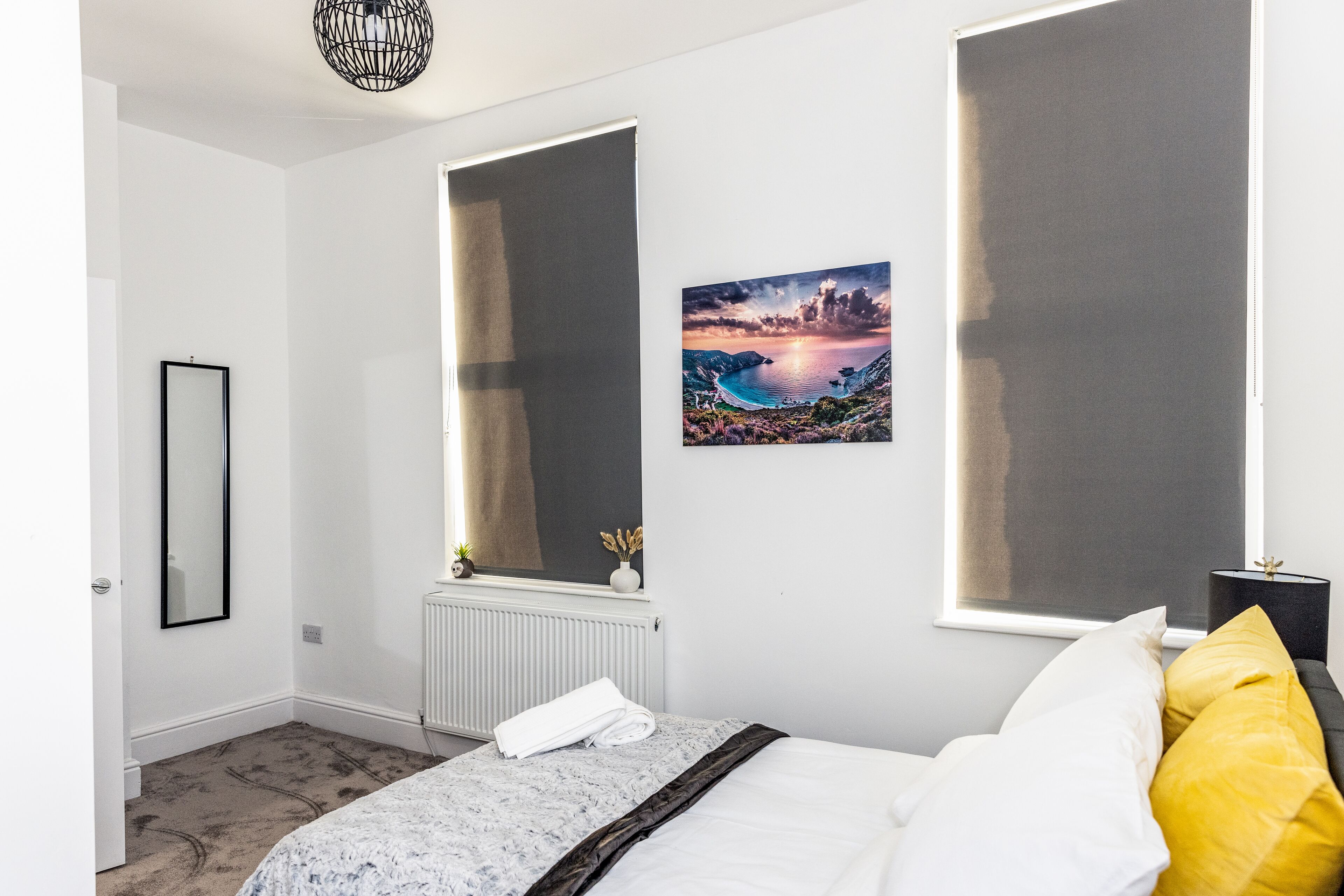 Une chambre à coucher avec un lit, une fenêtre donnant sur un beau paysage, un radiateur et un miroir au mur.