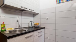 Een moderne keuken met een roestvrijstalen spoelbak, een waterkoker en een fruitschaal op het aanrecht.
