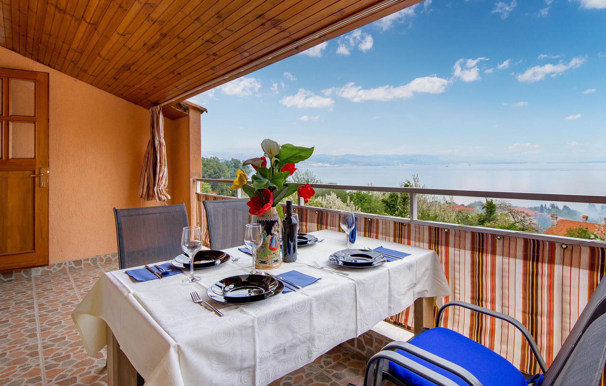 A dining table set on a balcony with a view of a lake and mountains.