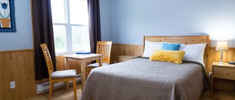 A bedroom with a wooden bed, a desk, and a chair.