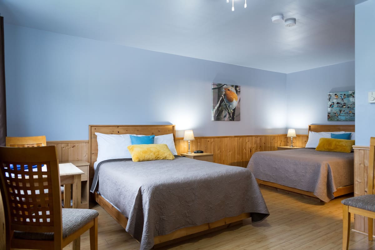 A room with two beds, wooden headboards, and a table with chairs.