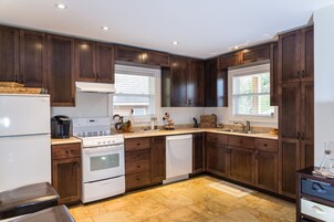 Une cuisine moderne avec des meubles en bois foncé, des appareils électroménagers blancs et un sol carrelé.