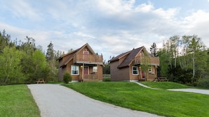Two wooden cabins with a gravel path leading to a picnic table. - Middle Brook Cottages & Chalets (Glenburnie-Birchy Head-Shoal Brook)